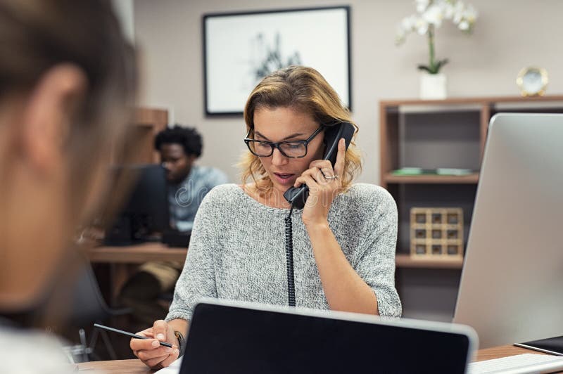 Mulher de negócios que fala no telefone no escritório foto de stock Mulher de negócios que fala no telefone no escritório foto de stock