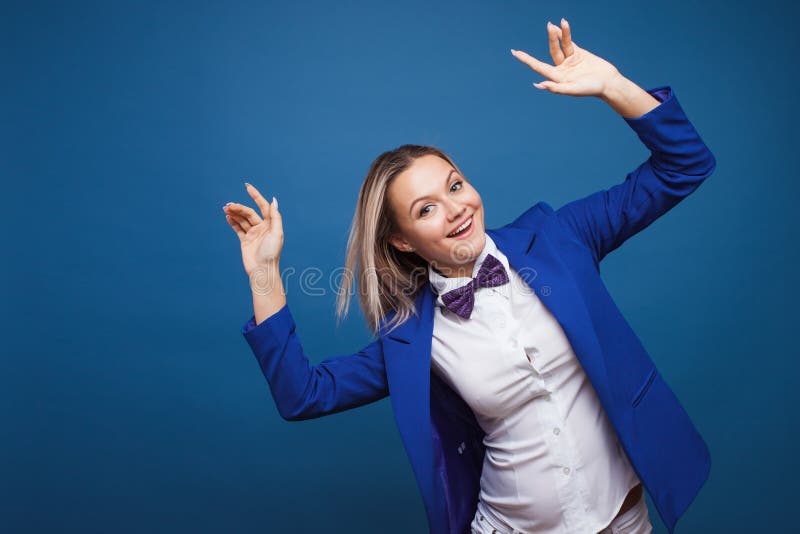 Mulher de negócios a saltar e a dançar com casaco azul estiloso e gravata-arco Retrato de uma garota alegre fotografia de stock royalty free Mulher de negócios a saltar e a dançar com casaco azul estiloso e gravata-arco Retrato de uma garota alegre fotografia de stock royalty free