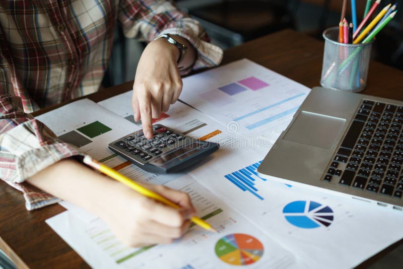 Mulher de negócios segurando um lápis para analisar o plano de marketing com calculadora no balcão de madeira no escritório Conce imagem de stock royalty free Mulher de negócios segurando um lápis para analisar o plano de marketing com calculadora no balcão de madeira no escritório Conce imagem de stock royalty free