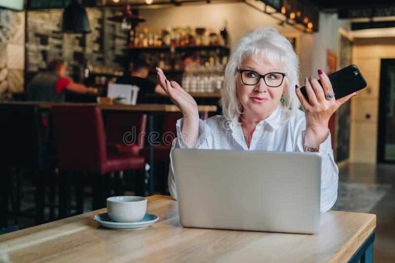 A mulher de negócios surpreendida está sentando-se na tabela na frente do portátil a imagens de stock A mulher de negócios surpreendida está sentando-se na tabela na frente do portátil a imagens de stock