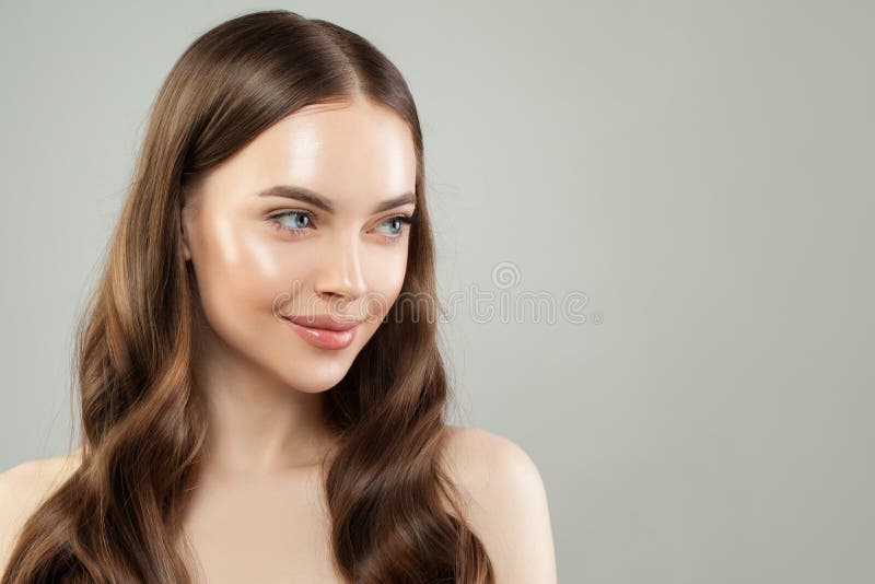 Smiling woman with clear skin and healthy hair on gray background. Beautiful face close up. Skincare and facial treatment concept. Smiling woman with clear skin and healthy hair on gray background. Beautiful face close up. Skincare and facial treatment concept.