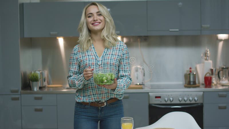 Mulher de sorriso com salada na cozinha