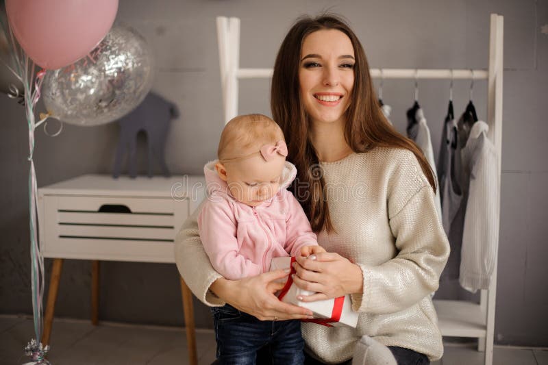 Mulher de sorriso e sua filha pequena bonito que guardam um presente foto de stock royalty free Mulher de sorriso e sua filha pequena bonito que guardam um presente foto de stock royalty free