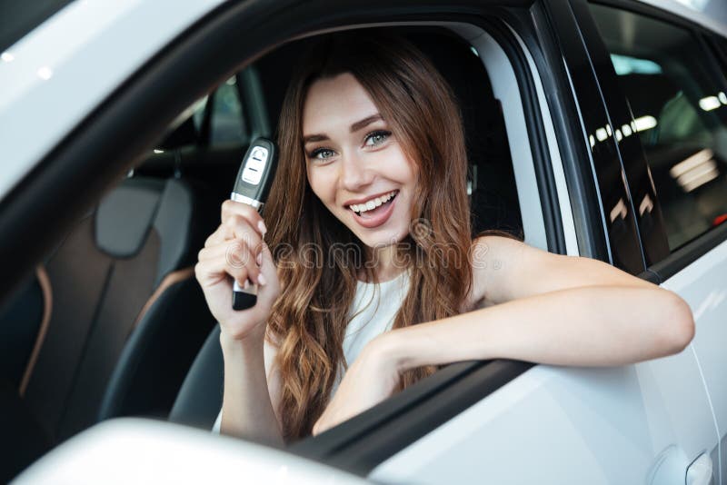 Mulher de sorriso feliz que senta-se dentro de seu carro novo foto de stock royalty free Mulher de sorriso feliz que senta-se dentro de seu carro novo foto de stock royalty free