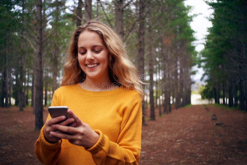 Mulher de sorriso nova na floresta usando o telefone celular imagens de stock royalty free Mulher de sorriso nova na floresta usando o telefone celular imagens de stock royalty free