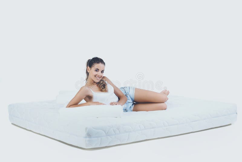 Mulher de sorriso nova que encontra-se no colchão ortopédico imagem de stock royalty free Mulher de sorriso nova que encontra-se no colchão ortopédico imagem de stock royalty free