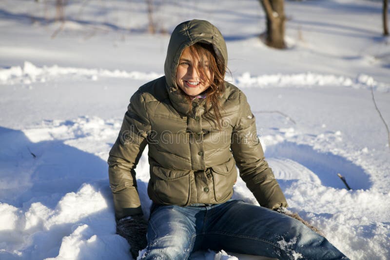Mulher de sorriso que senta-se na neve fotografia de stock royalty free Mulher de sorriso que senta-se na neve fotografia de stock royalty free