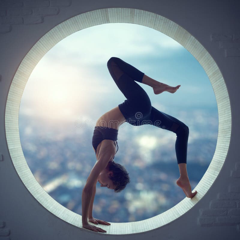 A mulher desportiva bonita do iogue do ajuste pratica o asana Eka Pada Urdhva Dhanurasana da ioga em uma janela redonda foto de stock A mulher desportiva bonita do iogue do ajuste pratica o asana Eka Pada Urdhva Dhanurasana da ioga em uma janela redonda foto de stock