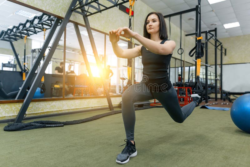 Mulher desportiva bonita nova que exercita no sistema das correias da aptid?o no gym Aptid?o, esporte, treinamento, e conceito sa fotografia de stock Mulher desportiva bonita nova que exercita no sistema das correias da aptid?o no gym Aptid?o, esporte, treinamento, e conceito sa fotografia de stock
