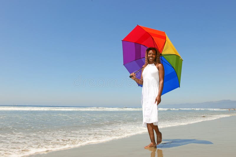 Mulher do americano africano na praia que prende um Umb fotos de stock royalty free Mulher do americano africano na praia que prende um Umb fotos de stock royalty free
