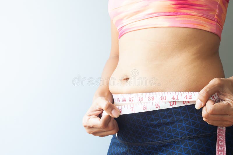 Mulher do emagrecimento com gordura da barriga, gordura de medição da barriga da mulher desportiva