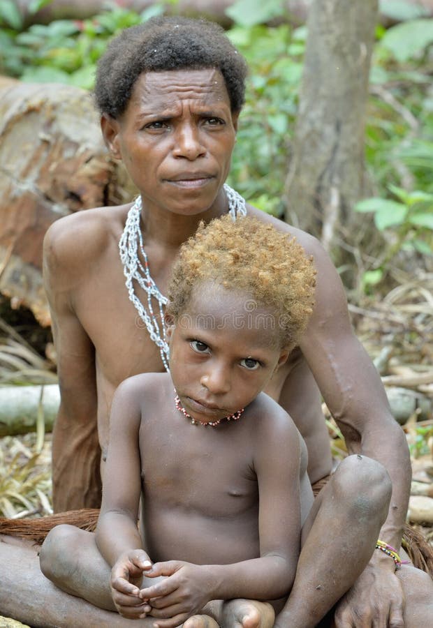 WILD JUNGLE, IRIAN JAYA, NEW GUINEA, INDONESIA - MAY 19, 2016: Papuan woman and little boy of Korowai tribe in the deep jungle of New Guinea. Irian Jaya. Indonesia. May 19, 2016. WILD JUNGLE, IRIAN JAYA, NEW GUINEA, INDONESIA - MAY 19, 2016: Papuan woman and little boy of Korowai tribe in the deep jungle of New Guinea. Irian Jaya. Indonesia. May 19, 2016