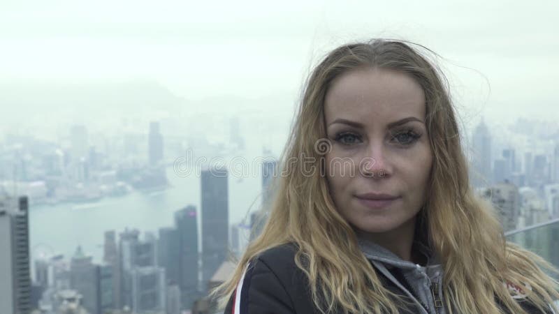 Mulher do retrato que olha à câmera quando panorama da cidade de Hong Kong do curso de Victoria máxima Mulher europeia do turista video estoque Mulher do retrato que olha à câmera quando panorama da cidade de Hong Kong do curso de Victoria máxima Mulher europeia do turista video estoque