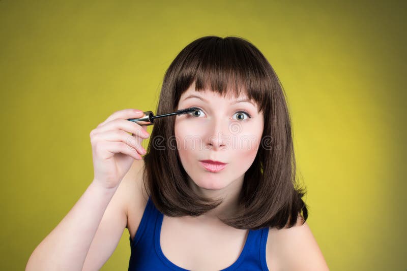Mulher do rímel da composição que prepara-se a vista in camera como em um espelho Imagem engraçada do modelo de forma fêmea novo imagem de stock Mulher do rímel da composição que prepara-se a vista in camera como em um espelho Imagem engraçada do modelo de forma fêmea novo imagem de stock