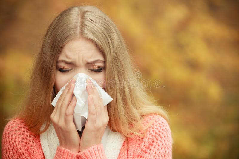 Mulher doente doente no parque do outono que espirra no tecido imagens de stock Mulher doente doente no parque do outono que espirra no tecido imagens de stock