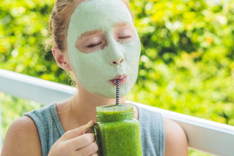 Mulher dos termas que aplica a máscara verde facial da argila Tratamentos da beleza Batido verde fresco com banana e espinafres c imagem de stock Mulher dos termas que aplica a máscara verde facial da argila Tratamentos da beleza Batido verde fresco com banana e espinafres c imagem de stock