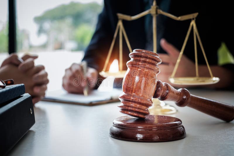 Mulher e advogados de negócio que discutem papéis do contrato com a escala de bronze na mesa de madeira no escritório Lei, serviç fotografia de stock Mulher e advogados de negócio que discutem papéis do contrato com a escala de bronze na mesa de madeira no escritório Lei, serviç fotografia de stock