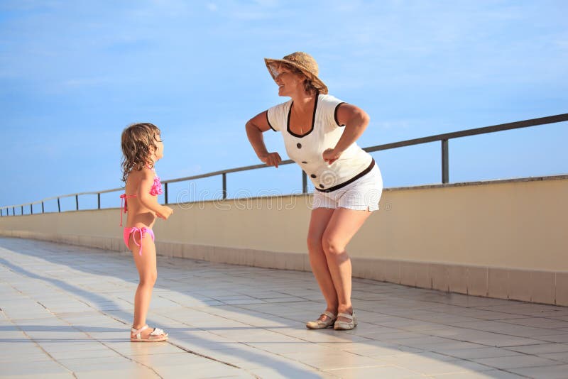 A mulher e a menina fazem o exercício da manhã na varanda fotos de stock A mulher e a menina fazem o exercício da manhã na varanda fotos de stock