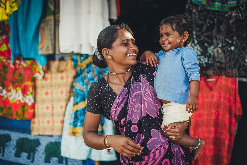 A mulher e o bebê indianos não identificados em seus braços estão sorrindo com muito foto de stock A mulher e o bebê indianos não identificados em seus braços estão sorrindo com muito foto de stock