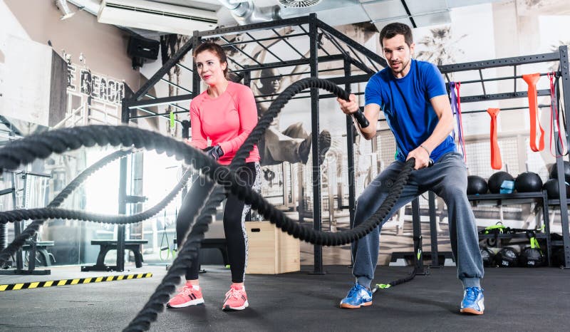 A mulher e o homem no treinamento funcional do gym com batalha rope imagens de stock royalty free A mulher e o homem no treinamento funcional do gym com batalha rope imagens de stock royalty free