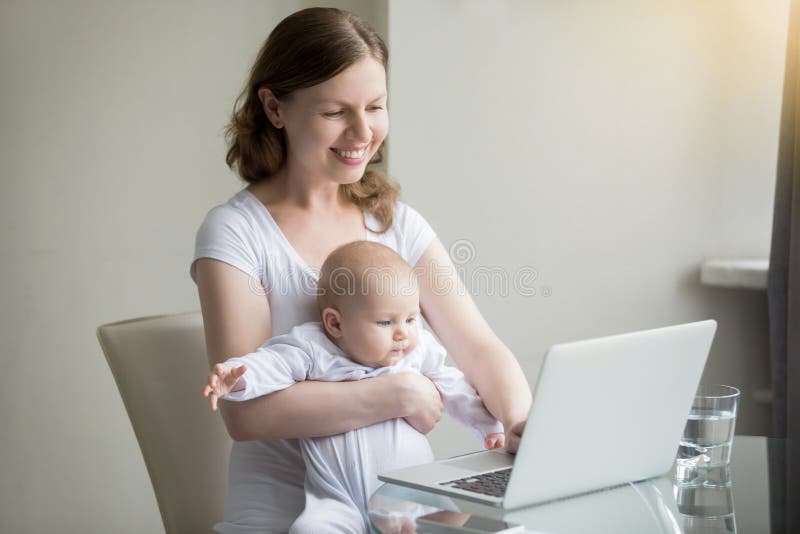 Mulher e um bebê perto do portátil imagem de stock Mulher e um bebê perto do portátil imagem de stock