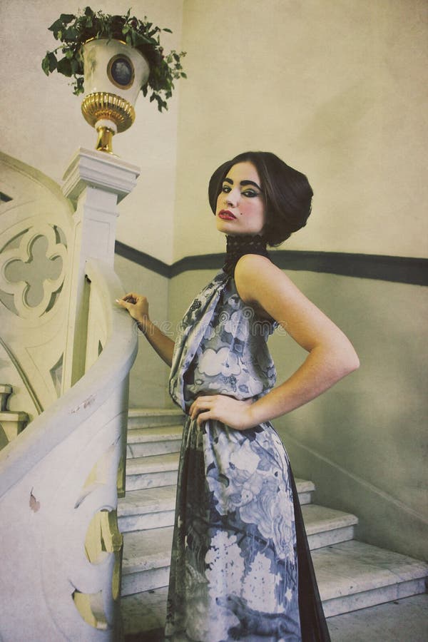 Mulher elegante no vestido longo em escadas do vintage imagens de stock Mulher elegante no vestido longo em escadas do vintage imagens de stock