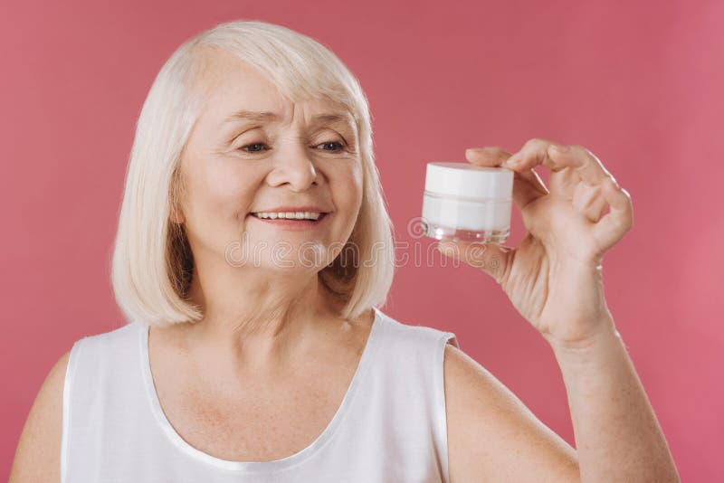 Mulher encantador agradável que olha o creme de levantamento da pele imagens de stock Mulher encantador agradável que olha o creme de levantamento da pele imagens de stock