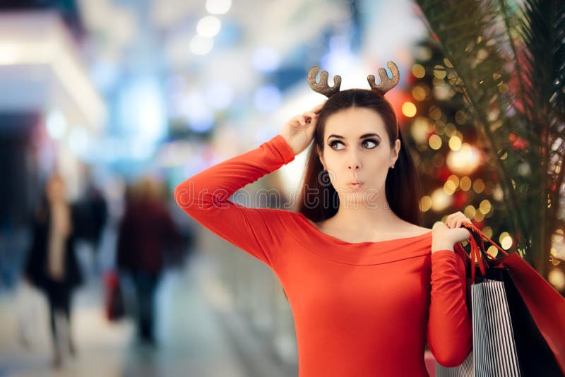 Mulher engraçada com compra da faixa dos chifres da rena do Natal imagem de stock