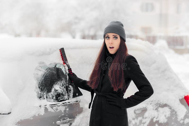 Mulher engraçada com uma escova que remove a neve do carro fotos de stock