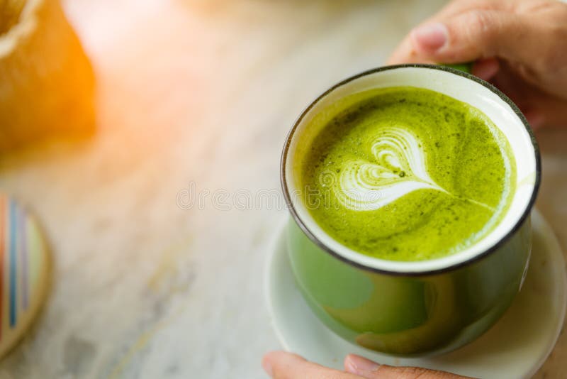 A mulher entrega manter o copo do chá verde quente com coração dado forma fotos de stock A mulher entrega manter o copo do chá verde quente com coração dado forma fotos de stock