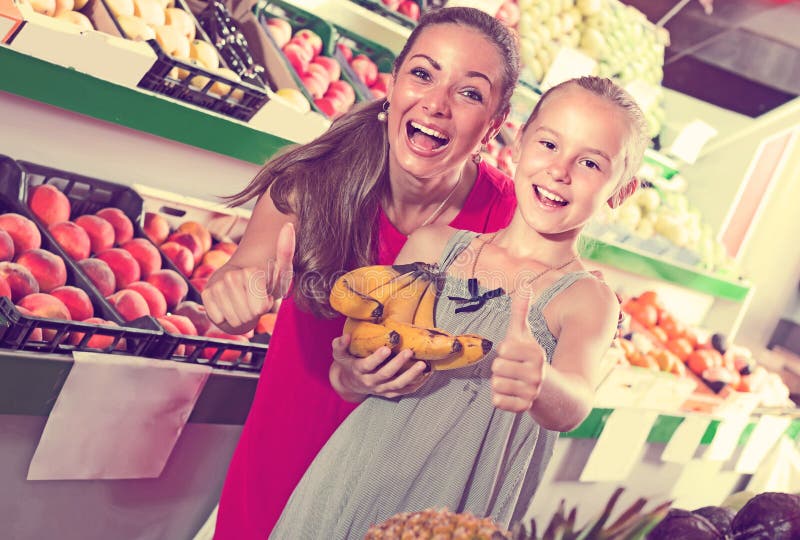 Mulher entusiasmado com a filha no mercado de fruto imagens de stock Mulher entusiasmado com a filha no mercado de fruto imagens de stock