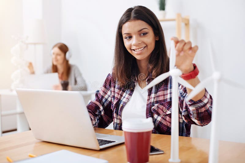 Renewable energy. Young motivated professional engineer sitting in class and developing her idea about wind energy while making some vivid models. Renewable energy. Young motivated professional engineer sitting in class and developing her idea about wind energy while making some vivid models