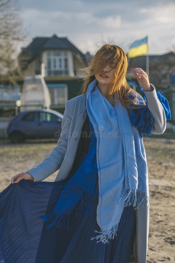 Mulher europeia lindo no revestimento e no vestido mornos em uma caminhada no parque perto do rio Tempo ventoso Sua roupa voa no imagens de stock royalty free Mulher europeia lindo no revestimento e no vestido mornos em uma caminhada no parque perto do rio Tempo ventoso Sua roupa voa no imagens de stock royalty free
