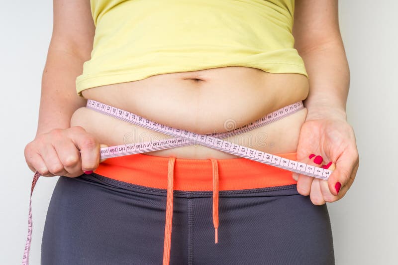 A mulher excesso de peso com fita está medindo a gordura na barriga