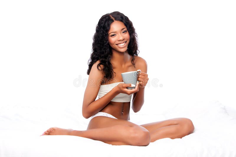 Mulher feliz bonita com o café delicioso que senta-se na cama branca imagem de stock royalty free Mulher feliz bonita com o café delicioso que senta-se na cama branca imagem de stock royalty free