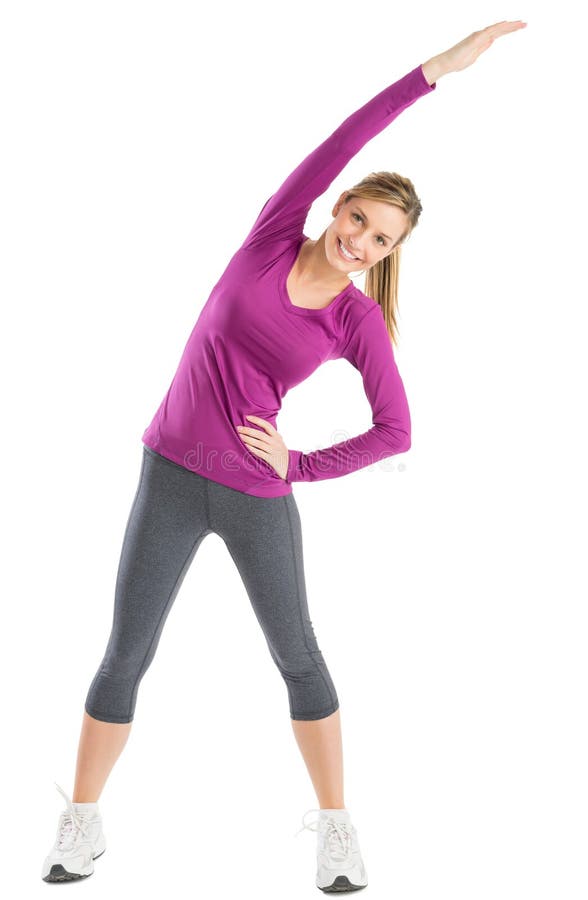 Full length portrait of happy young woman with arms raised doing stretching exercise against white background. Full length portrait of happy young woman with arms raised doing stretching exercise against white background