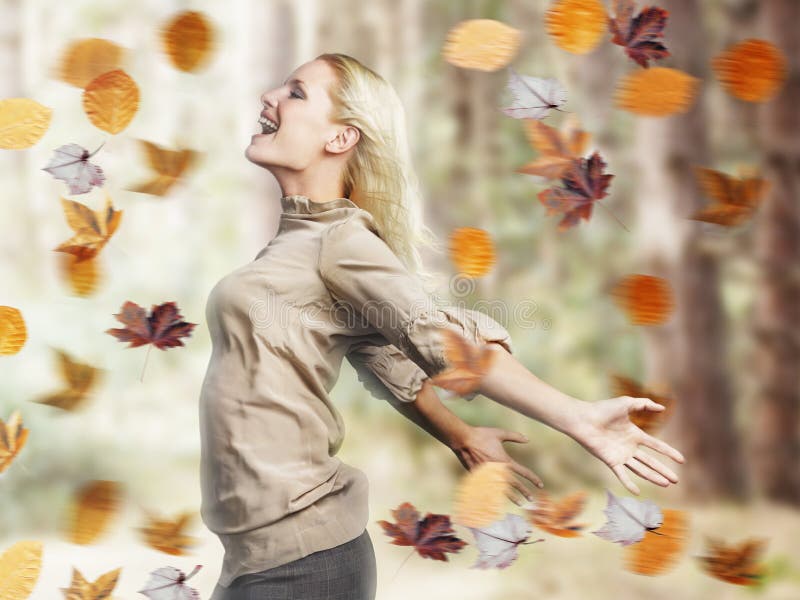 Mulher feliz com os braços estendido entre as folhas da queda