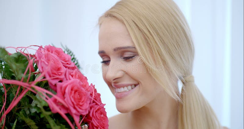 Mulher feliz com um ramalhete de Rose Flowers cor-de-rosa