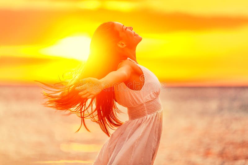 Happy woman feeling free with open arms in sunshine at beach sunset. Freedom and carefree enjoyment girl enjoying life. Beautiful woman in white dress for success, health, hope and faith concept. Happy woman feeling free with open arms in sunshine at beach sunset. Freedom and carefree enjoyment girl enjoying life. Beautiful woman in white dress for success, health, hope and faith concept.