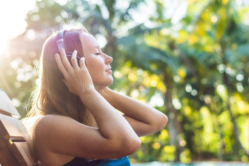 Mulher feliz do smartphone que relaxa perto da piscina que escuta com earbuds a fluência da música Menina bonita que usa seu phon fotografia de stock royalty free Mulher feliz do smartphone que relaxa perto da piscina que escuta com earbuds a fluência da música Menina bonita que usa seu phon fotografia de stock royalty free