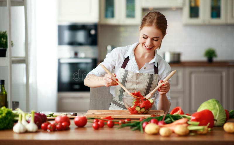 Mulher feliz que prepara a salada vegetal na cozinha fotos de stock Mulher feliz que prepara a salada vegetal na cozinha fotos de stock