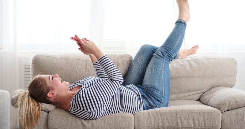 Mulher feliz que relaxa e que toma o selfie usando a câmera do telefone celular