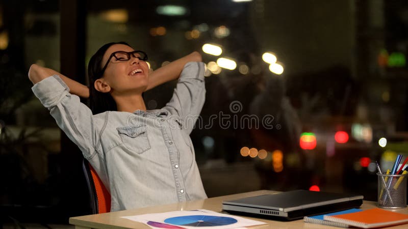Mulher feliz que relaxa na cadeira, satisfeita com o dia de trabalho produtivo, aut?nomo imagem de stock royalty free Mulher feliz que relaxa na cadeira, satisfeita com o dia de trabalho produtivo, aut?nomo imagem de stock royalty free