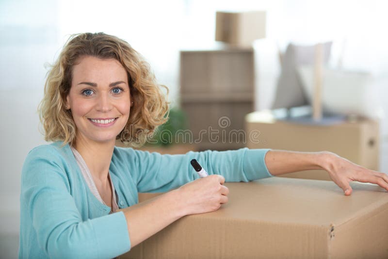 happy woman labeling moving box at home information. happy woman labeling moving box at home information