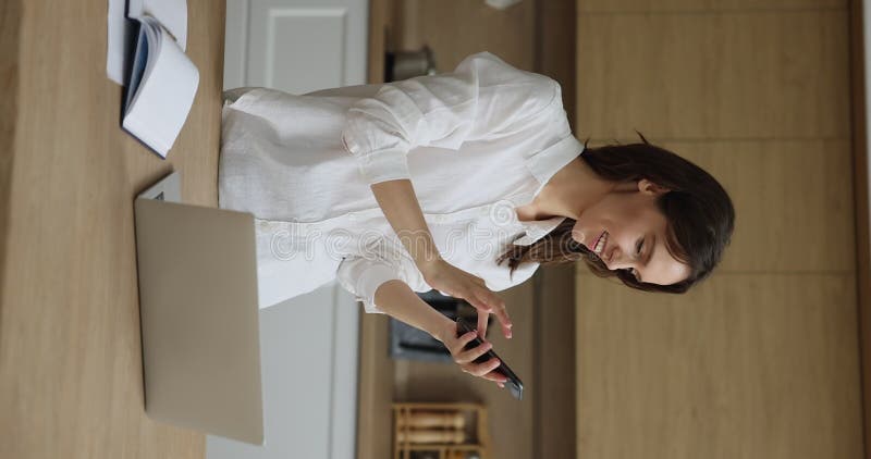 Mulher fotografada vertical usa smartphone na cozinha