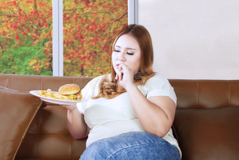 Mulher gorda que come a comida lixo no sofá