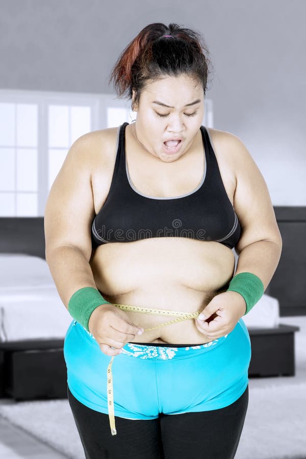 Mulher gorda que mede sua cintura imagem de stock royalty free Mulher gorda que mede sua cintura imagem de stock royalty free