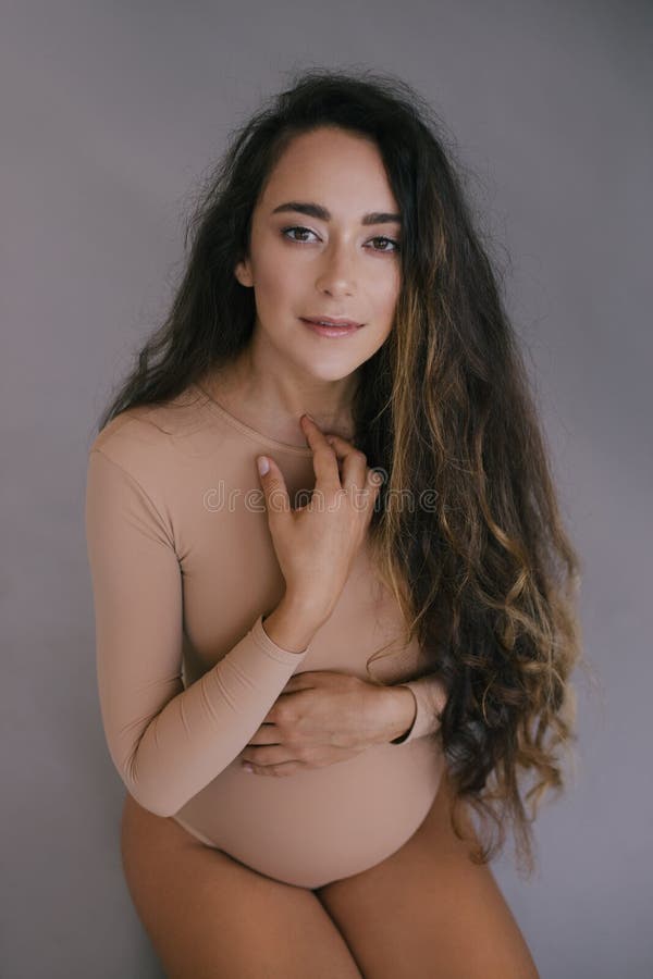 Mulher gravida bonita com cabelo longo no fundo cinzento foto de stock Mulher gravida bonita com cabelo longo no fundo cinzento foto de stock