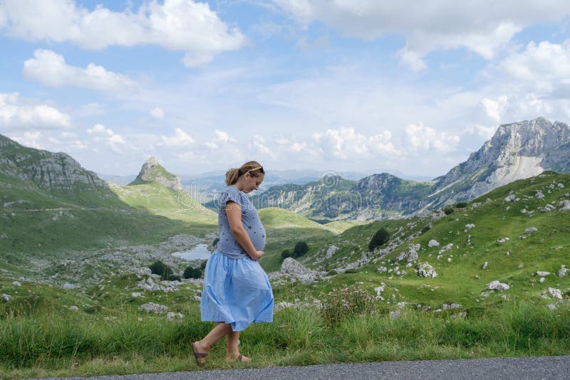 Mulher gravida bonita no fundo de uma paisagem da montanha imagem de stock Mulher gravida bonita no fundo de uma paisagem da montanha imagem de stock