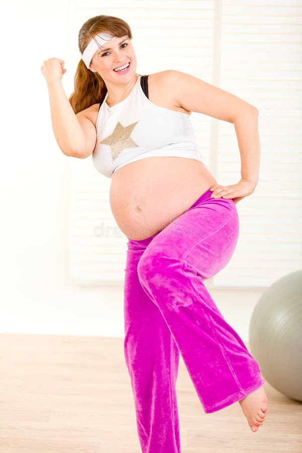 Mulher gravida de sorriso que faz exercícios da aptidão fotografia de stock royalty free Mulher gravida de sorriso que faz exercícios da aptidão fotografia de stock royalty free